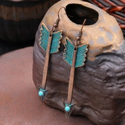 Macro d'une boucle d'oreille rétro en bronze en forme de flèche avec perle bleue