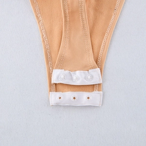 Close-up of three white plastic snap buttons on a nude pleated V-neck jumpsuit