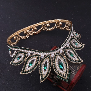 Detailed macro view of baroque gold crown with emerald rhinestones on vintage wooden box