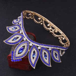 Close-up of golden Baroque bridal crown with blue and clear rhinestones on black background