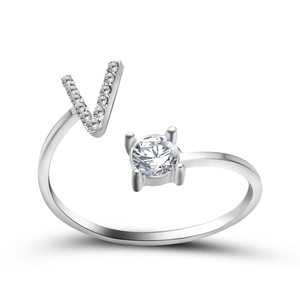 Detail of silver open ring featuring a crystal-studded V letter and round center stone