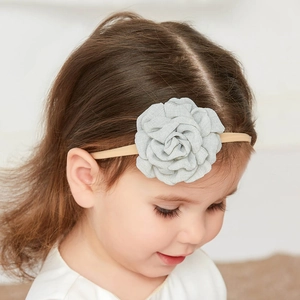Children's light gray fabric flower headband on a beige elastic band worn by a toddler