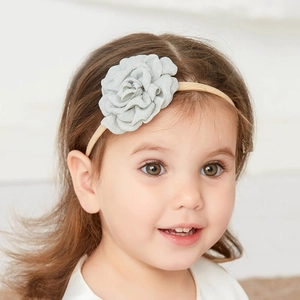 Close-up of a smiling toddler girl wearing a light green fabric floral headband accessory