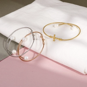 Three-piece set of twisted steel cable bangles with pearls and cross in silver and gold