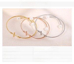 Detail of cross charm and shell pearl on woven stainless steel bracelet band