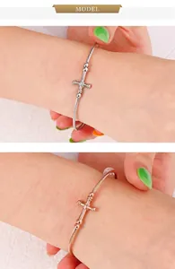 Detail of twisted cable cuff bracelet with religious cross motif in silver and rose gold