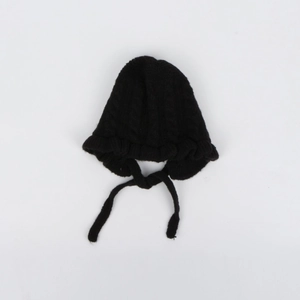 Detailed close-up of a black cable knit baby bonnet with ruffle edges and secure chin straps