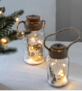 Detail of Christmas glass LED lanterns with miniature reindeer and pine trees
