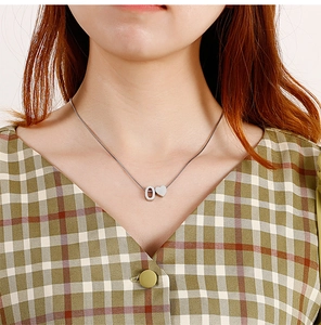 Detail of silver titanium heart and letter O pendant necklace worn on a model