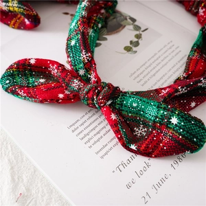 Detail of a Christmas knot headband featuring red and green plaid fabric with gold accents