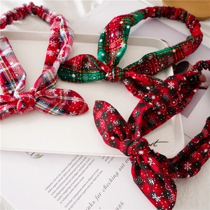 Detailed view of red and green plaid Christmas knot headbands with festive snowflake patterns