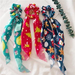 Christmas silk scrunchies with streamers in red, teal and navy blue colors on white fabric