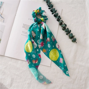 Detailed view of green Christmas scrunchie with long ribbons and festive holiday patterns