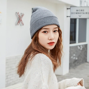 Close-up of a women's grey knitted beanie hat for winter warmth shown on a model