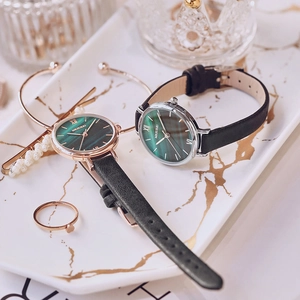 Detail of luxury green dial quartz watches with black leather straps and gold jewelry