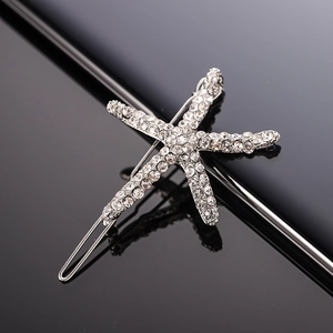 Macro shot of silver starfish hair clip with sparkling rhinestones on black reflection