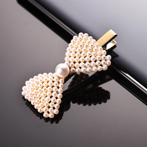 Elegant bow-shaped hair clip with white faux pearls and gold metal duckbill clamp