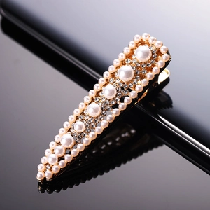 Elegant gold pearl hair clip with rhinestones for women shown on a black reflective surface