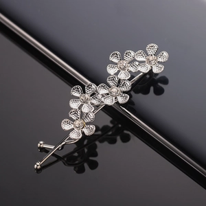 Silver branch hair clip with five floral patterns and crystal rhinestones on black surface