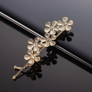 Detailed close-up of golden geometric hair clip with sparkling rhinestones and floral motif
