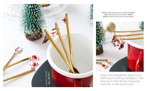 Detail of gold stainless steel spoons with festive Christmas pendants for coffee stirring