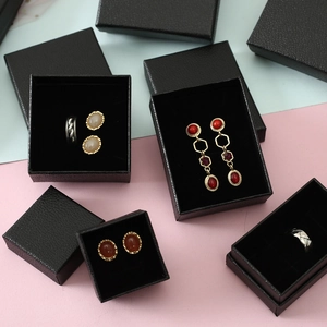 Black lychee texture jewelry boxes with rings and earrings on a split pastel background