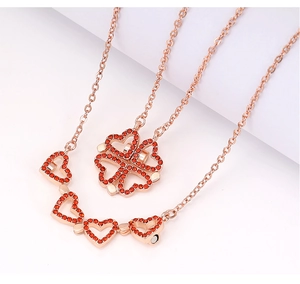 Detail showing red crystal heart necklace transforming into a lucky four-leaf clover design