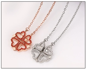 Macro detail of magnetic folding clover necklace in rose gold with red and white zircons