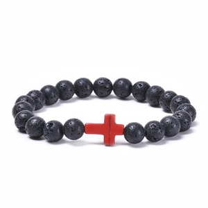 Detailed close-up of lava rock bracelet with red cross bead and natural stone texture