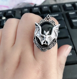 Macro shot of silver-tone bat ring featuring a black oval gemstone and vintage pattern