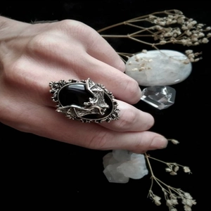 Gothic silver bat ring with oval black gemstone displayed with dried flowers