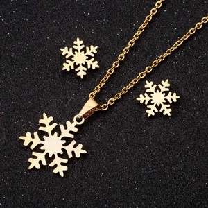 Goldenes Edelstahl-Schmuckset mit Schneeflocken-Anhänger und Ohrringen auf dunklem Hintergrund