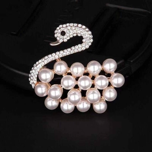 Detailed view of elegant rose gold swan brooch with white pearls and sparkling crystals