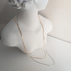 Chic silver and gold snake bone chains shown on a classic white bust sculpture