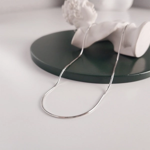 Detail of silver 925 sterling silver snake chain necklace on white marble statue