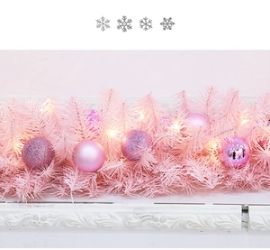 Detail of pink Christmas garland with festive ornaments and warm LED fairy lights