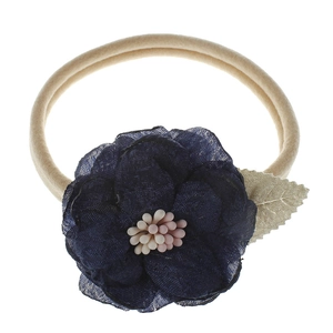 Detail of baby headband with dark blue fabric flower, golden leaf, and bead center