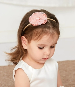 Detailed view of pink fabric flower headband on a young girl's head for holiday hair styling