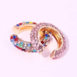 Macro detail of gold C-shape ear clips with multi-color and pink rhinestones