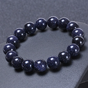 Blue goldstone bead bracelet with sparkling starry sky effect on a textured gray background