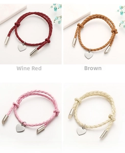 Detail view of heart charm braided cord bracelets in wine, brown, pink, and yellow colors