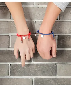 Detail of red and blue braided PU cord bracelets with silver heart charms on wrist