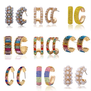 Detail view showing nine styles of C-shaped gold earrings with pearls and colorful zircons