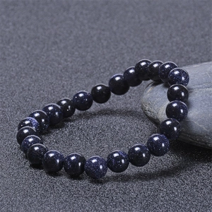 Macro detail of blue sandstone beaded bracelet with starlight effect on smooth pebble
