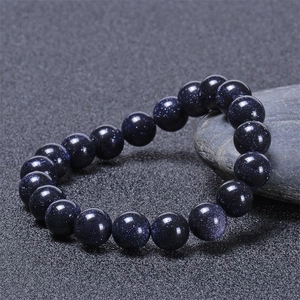 Macro shot of blue sandstone bead bracelet on natural grey stones with galaxy sparkle effect