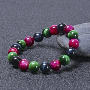 Vue détaillée du bracelet en perles d'oeil de tigre coloré sur pierre sombre avec effet