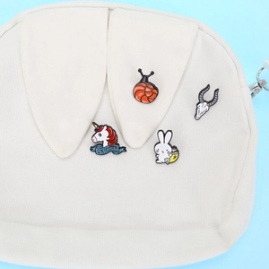 Detailed macro shot of enamel pins on a canvas bag featuring colorful animal designs
