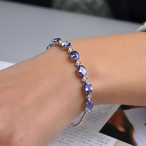 Close-up of a silver bracelet featuring oval blue sapphires and sparkling diamond accents