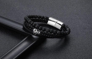 Close-up of punk skull bracelet with black matte beads and woven leather strap