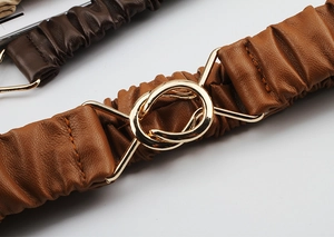 Detail of warm brown elastic waist belt featuring a gold interlocking double ring buckle